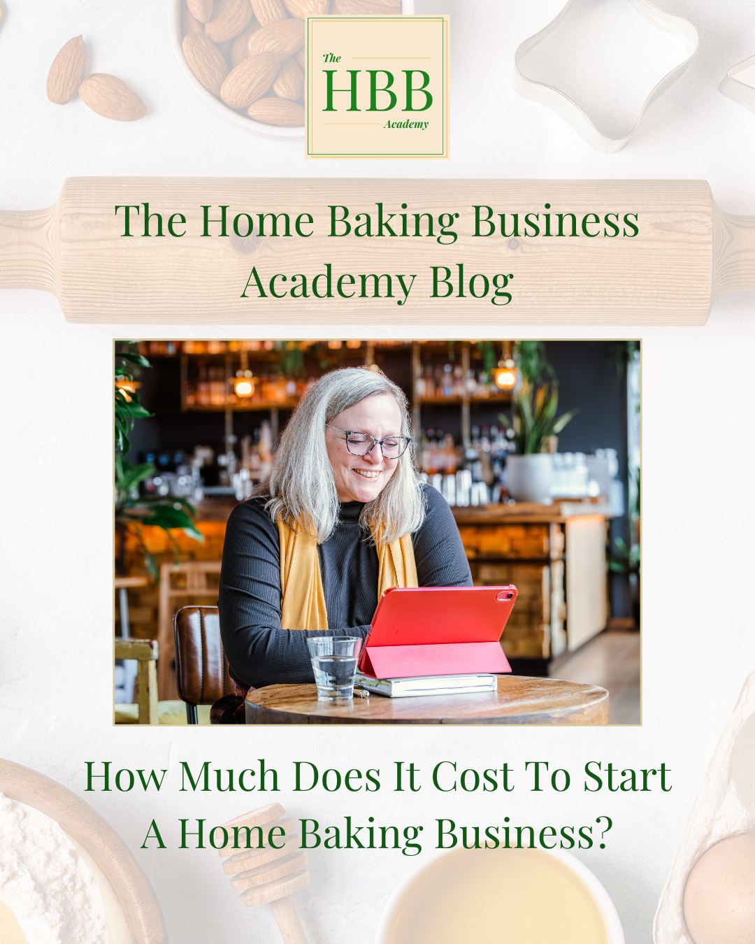 A promotional blog image from The Home Baking Business Academy. At the top, a logo reads “The HBB Academy.” Below, a smiling woman with shoulder-length grey hair and glasses sits in a cozy café, using a red tablet with a notebook and glass of water on the table. The text reads: “The Home Baking Business Academy Blog — How Much Does It Cost To Start A Home Baking Business?” The background features baking ingredients like flour, almonds, and cookie cutters.